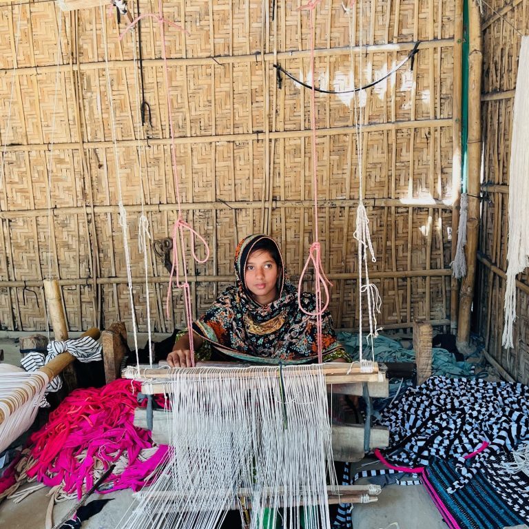 A woman making floormats using pit-loom at Baliadanghi